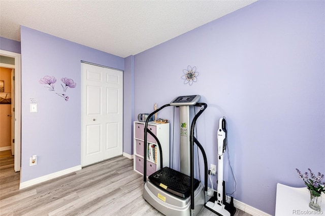 862 Centennial Way, Bennett, CO 80102 - workout area featuring light wood-style flooring, baseboards, and a textured ceiling