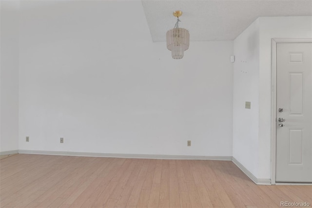 spare room with baseboards and light wood finished floors