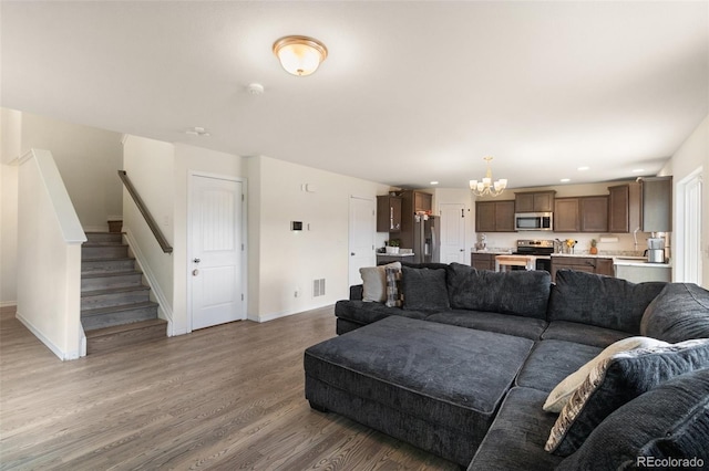 living room featuring a notable chandelier, recessed lighting, wood finished floors, baseboards, and stairs