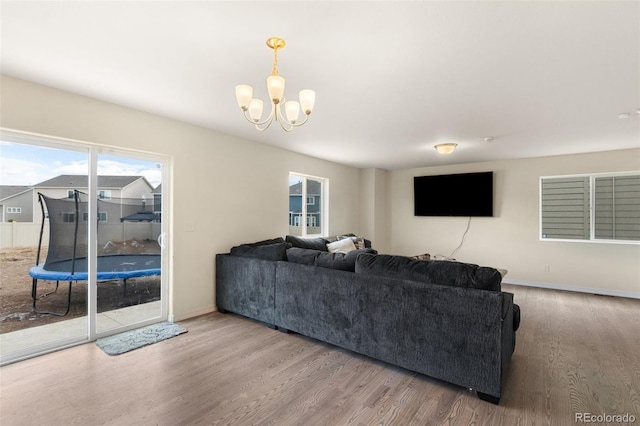 living area featuring baseboards, an inviting chandelier, and wood finished floors