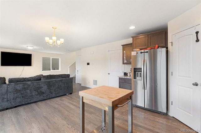 kitchen with open floor plan, wood finished floors, stainless steel fridge, and a notable chandelier