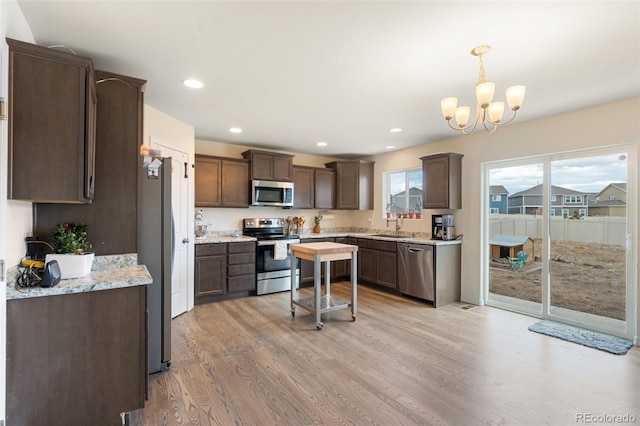 kitchen featuring stainless steel appliances, dark brown cabinets, light wood-type flooring, a sink, and recessed lighting