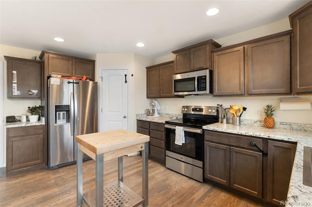 kitchen featuring appliances with stainless steel finishes, light wood-style flooring, dark brown cabinetry, and recessed lighting