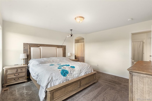 bedroom with dark colored carpet, arched walkways, and baseboards