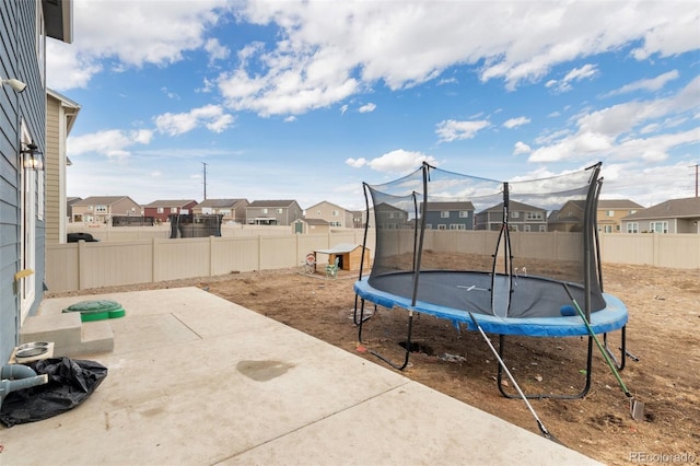 view of patio featuring a fenced backyard, a trampoline, and a residential view