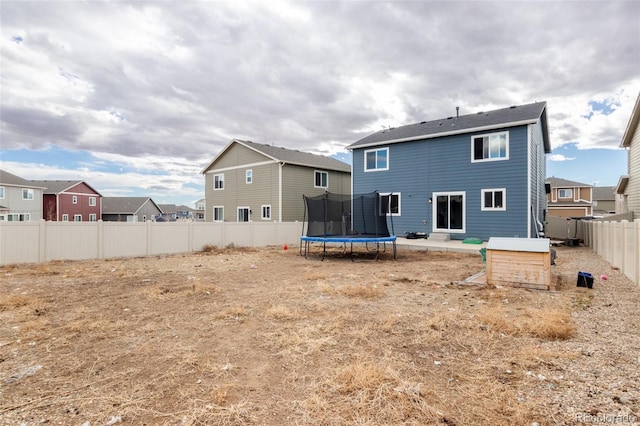 back of property with a trampoline, a residential view, and a fenced backyard