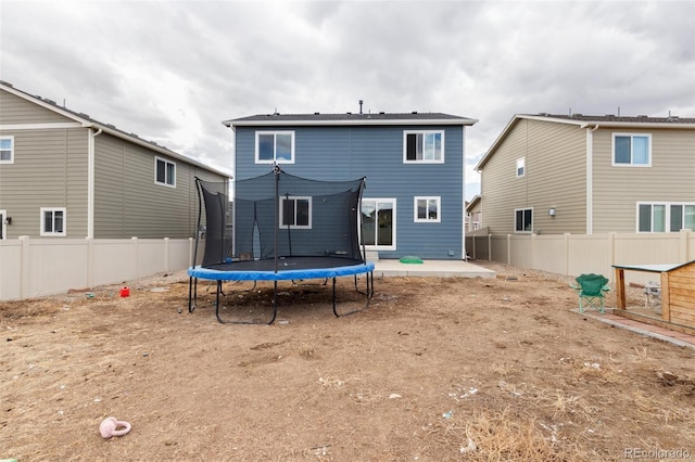 rear view of property featuring a fenced backyard, a trampoline, and a patio