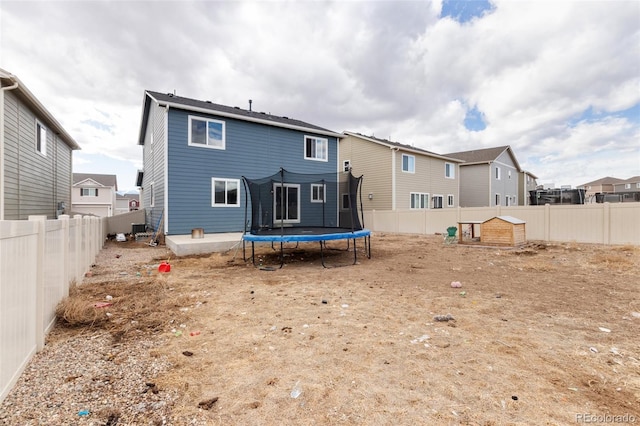 rear view of house featuring a fenced backyard and a trampoline