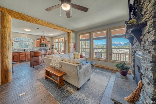 11398 County Road 302, Buena Vista, CO 81211 - living room with a ceiling fan, a stone fireplace, beam ceiling, and wood finished floors