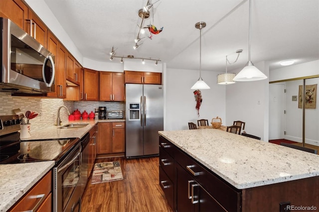 kitchen with a sink, dark wood-type flooring, a kitchen island, decorative backsplash, and appliances with stainless steel finishes