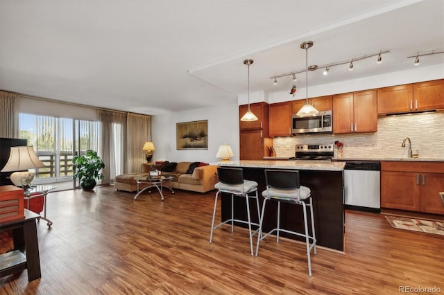 kitchen with open floor plan, appliances with stainless steel finishes, tasteful backsplash, and a sink