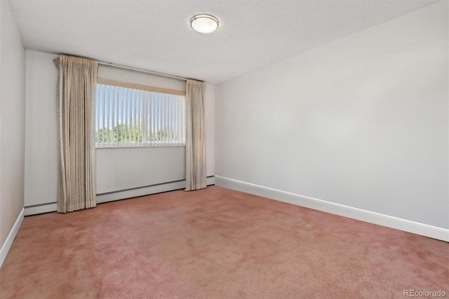 spare room featuring a baseboard heating unit, baseboards, and light carpet