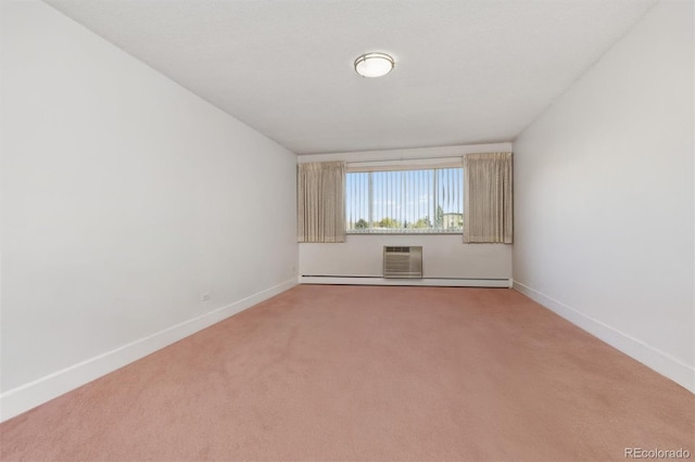 unfurnished room featuring a wall mounted air conditioner, light carpet, a baseboard heating unit, and baseboards