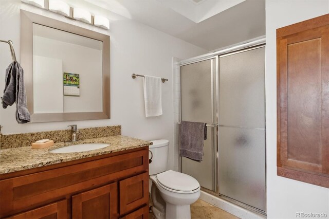 bathroom featuring toilet, vanity, and a stall shower