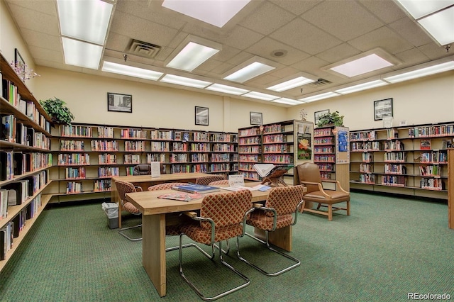 interior space featuring visible vents, carpet flooring, and wall of books