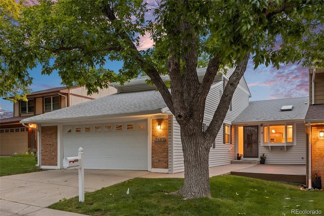 7483 W Cedar Cir, Lakewood, CO 80226 - view of front of home with concrete driveway, an attached garage, brick siding, and a yard