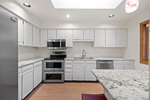 7483 W Cedar Cir, Lakewood, CO 80226 - kitchen with stainless steel appliances, a sink, a skylight, white cabinetry, and recessed lighting