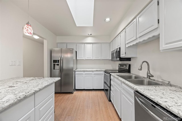 7483 W Cedar Cir, Lakewood, CO 80226 - kitchen with stainless steel appliances, a sink, light wood finished floors, pendant lighting, and a skylight