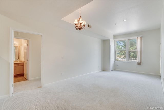 spare room featuring a chandelier, light colored carpet, visible vents, and baseboards