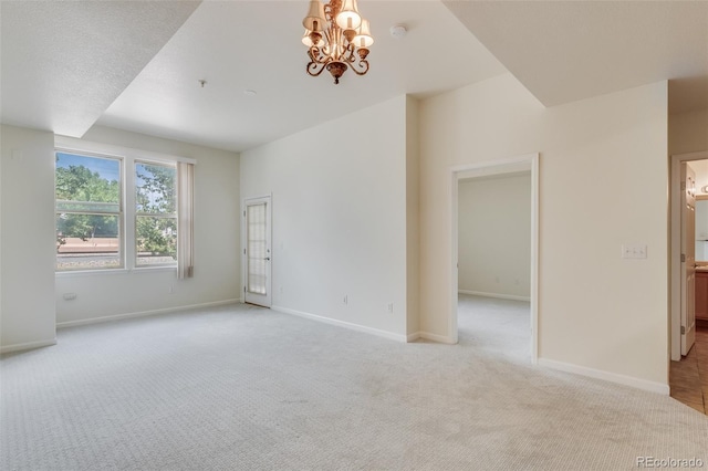 empty room with light carpet, baseboards, and a notable chandelier