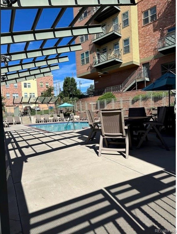 view of patio with a community pool and fence