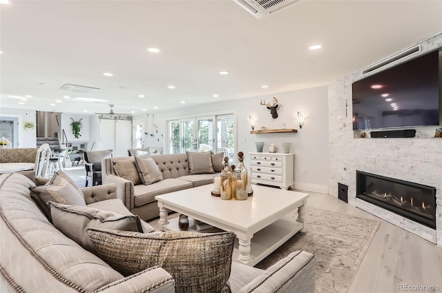 living area featuring visible vents, baseboards, a fireplace, recessed lighting, and wood finished floors