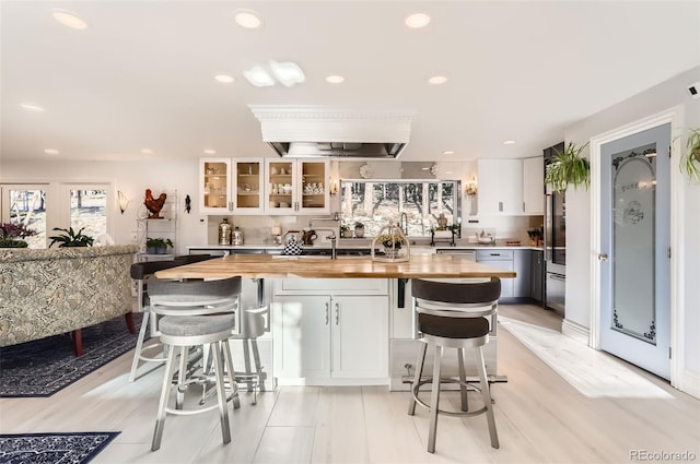 kitchen featuring white cabinetry, butcher block countertops, recessed lighting, and a kitchen bar