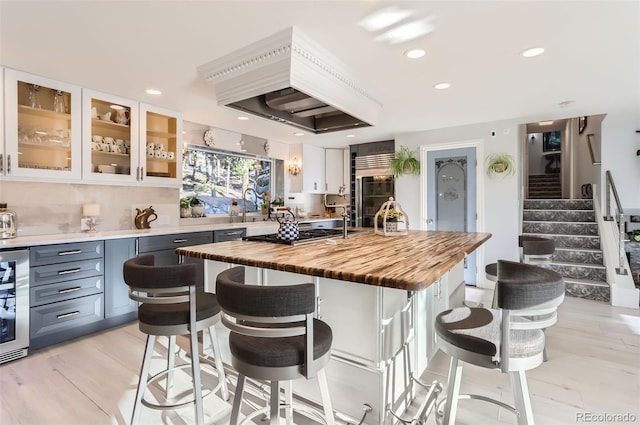kitchen with built in refrigerator, butcher block countertops, recessed lighting, and glass insert cabinets