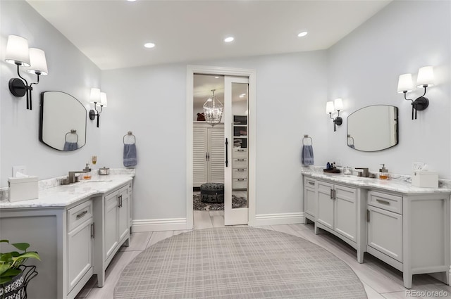 bathroom with recessed lighting, two vanities, a chandelier, and a sink