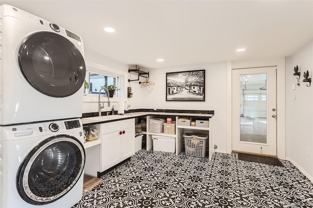 washroom featuring baseboards, a sink, stacked washing maching and dryer, recessed lighting, and cabinet space