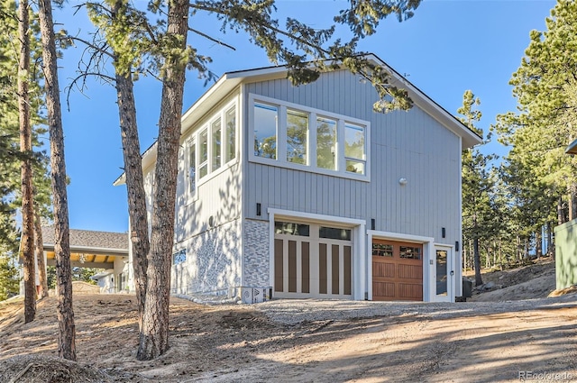 view of side of home with dirt driveway and a garage