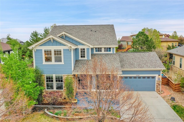 view of front of property with roof with shingles, an attached garage, stone siding, board and batten siding, and concrete driveway