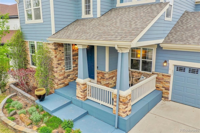 view of exterior entry featuring covered porch, a shingled roof, and stone siding