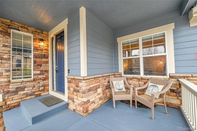 doorway to property with a porch and stone siding