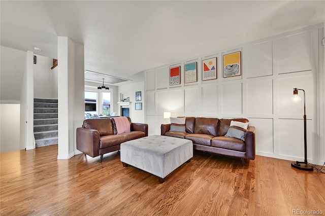 living area with stairway, a decorative wall, and wood finished floors