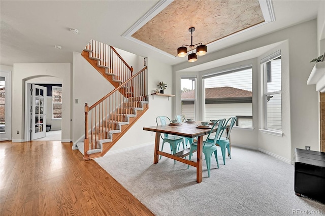 dining room with baseboards, arched walkways, wood finished floors, and stairway