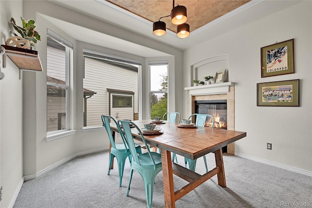 carpeted dining area with baseboards, an inviting chandelier, and a tile fireplace