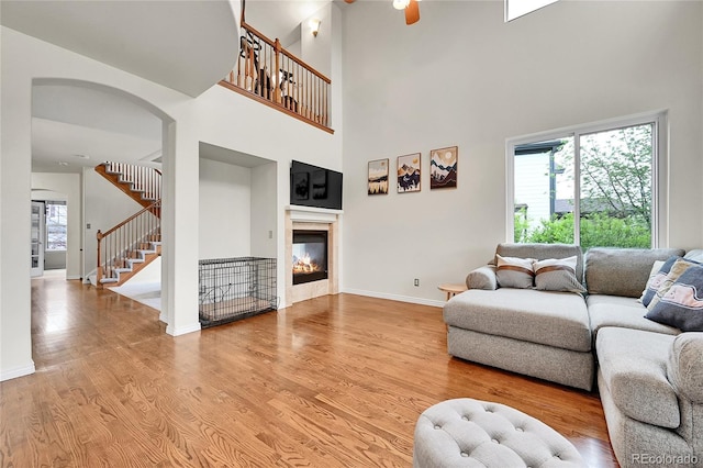 living room with a towering ceiling, baseboards, stairway, and light wood-style floors
