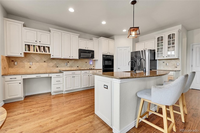 kitchen featuring a sink, white cabinetry, black appliances, and a kitchen bar