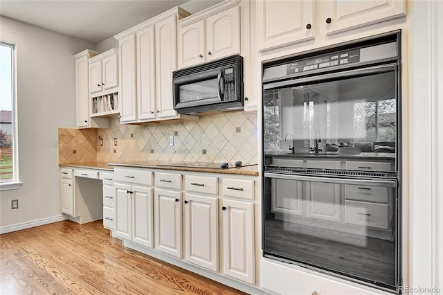 kitchen with backsplash, baseboards, black appliances, light wood-style floors, and white cabinetry
