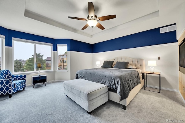 carpeted bedroom with visible vents, baseboards, ceiling fan, and a tray ceiling