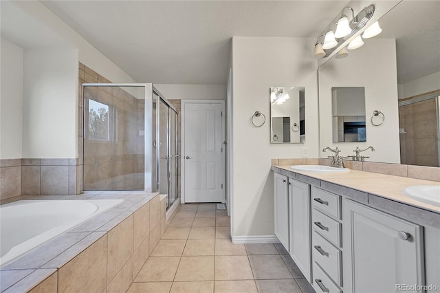 bathroom featuring a sink, tile patterned flooring, a shower stall, and a garden tub
