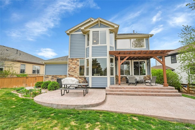 rear view of house with fence, a pergola, stone siding, a patio, and a yard