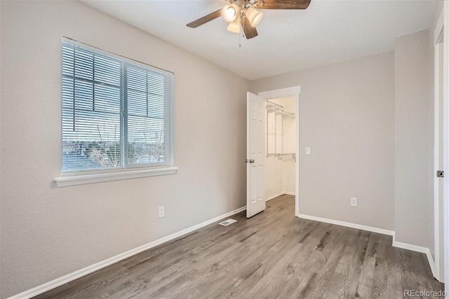 3401 W Milan Ave, Denver, CO 80236 - unfurnished bedroom with wood finished floors, baseboards, a spacious closet, a closet, and a ceiling fan