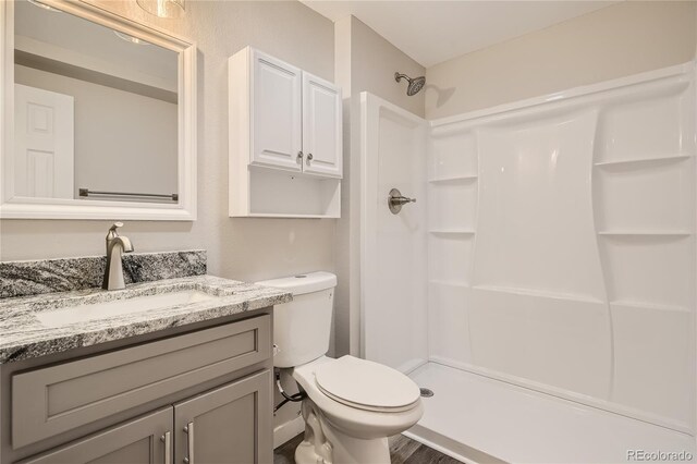 3401 W Milan Ave, Denver, CO 80236 - bathroom featuring a shower, toilet, vanity, and wood finished floors