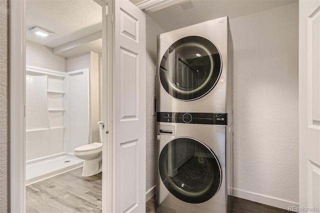 3401 W Milan Ave, Denver, CO 80236 - washroom featuring stacked washer / drying machine, wood finished floors, a textured wall, and baseboards