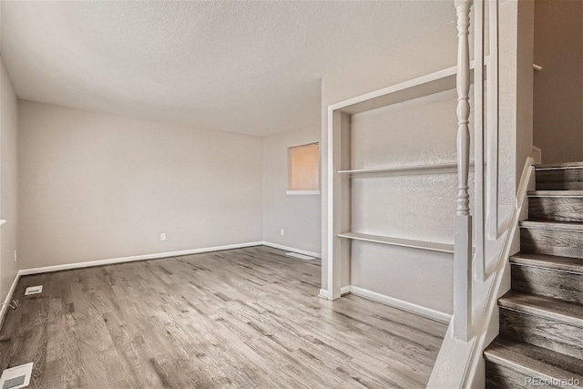 3401 W Milan Ave, Denver, CO 80236 - spare room featuring wood finished floors, baseboards, stairway, and a textured ceiling