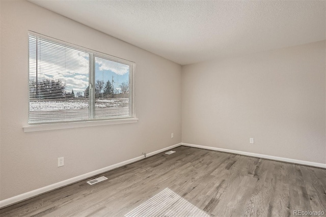 3401 W Milan Ave, Denver, CO 80236 - empty room with wood finished floors, baseboards, and a textured ceiling
