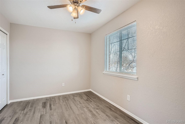 3401 W Milan Ave, Denver, CO 80236 - unfurnished bedroom featuring wood finished floors, multiple windows, baseboards, a closet, and a textured wall