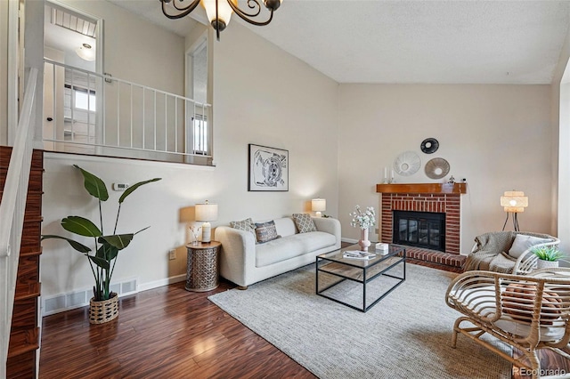 living room featuring baseboards, a brick fireplace, wood finished floors, and visible vents